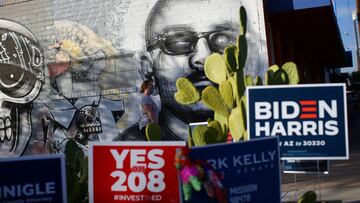 A woman walks past a graffiti on a wall in the majority Hispanic neighborhood of Maryvale in Phoenix, Arizona U.S., November 3, 2020. REUTERS/Edgard Garrido