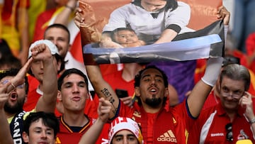 A Spain's supporter holds a placard with a picture showing Argentina's Lionel Messi posing with young Spain's forward #19 Lamine Yamal who was visiting a Barcelona locker room as part of a charity calendar�photo�shoot in 2007 ahead of the UEFA Euro 2024 final football match between Spain and England at the Olympiastadion in Berlin on July 14, 2024. (Photo by INA FASSBENDER / AFP)