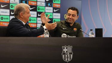 FC Barcelona President Joan Laporta (L) and Barcelona's Spanish coach Xavi react during a press conference at the Joan Gamper training ground in Sant Joan Despi, near Barcelona, on April 25, 2024. Xavi will remain as coach of Barcelona, the Spanish giants told AFP on April 24, despite having announced in January that he planned to quit at the end of the season due to the "cruel and unpleasant" nature of the job. (Photo by LLUIS GENE / AFP)