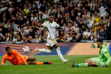 MADRID, 11/11/2023.- El delantero brasileño del Real Madrid Vinícius Júnior (c) disputa una posesión ante Cristian Mosquera (i) defensa del Valencia, y Giorgi Mamardashvili (d) guardameta georgiano del equipo ché durante el partido de la jornada 13 de LaLiga que Real Madrid y Valencia CF disputan este sábado en el estadio Santiago Bernabéu. EFE/ Mariscal
