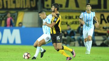 El jugador del Atlético Tucumán Rodrigo Aliendro protege el balón ante la marca de Hernán Petryk de Peñarol.