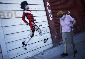 BUENOS AIRES, ARGENTINA - NOVEMBER 27: A woman walks past a mural of Diego Maradona on a wall outside Argentinos Juniors' Diego Armando Maradona Stadium on November 27, 2020 in Buenos Aires