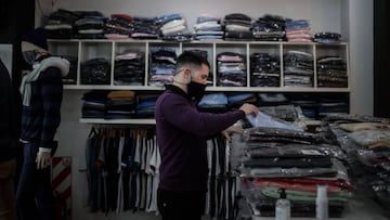 AME5200. BUENOS AIRES (ARGENTINA), 08/06/2020.- Un hombre acomoda ropa en su local hoy lunes, luego que el gobierno permitiera la apertura de zapaterías y locales textiles en Buenos Aires. Buenos Aires, la ciudad más afectada por el coronavirus en Argentina, autoriza desde este lunes reabrir sus puertas los comercios barriales de indumentaria y calzado, con medidas de distanciamiento pero sin probadores y, aunque se mantienen restringidas las celebraciones religiosas, se podrán transmitir ceremonias desde los templos, sin público y vía internet, al igual que ocurre con los espectáculos culturales. EFE/Juan Ignacio Roncoroni