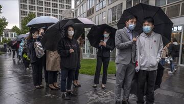 BEIJING, CHINA - APRIL 27: Office workers wait in line in the rain to take a nucleic acid test to detect COVID-19 at a makeshift testing site in the Central Business district in Chaoyang on April 27, 2022 in Beijing, China. China is trying to contain a sp