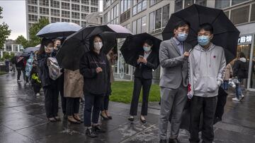 BEIJING, CHINA - APRIL 27: Office workers wait in line in the rain to take a nucleic acid test to detect COVID-19 at a makeshift testing site in the Central Business district in Chaoyang on April 27, 2022 in Beijing, China. China is trying to contain a sp