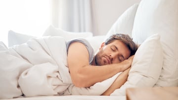 Home, bedroom and sleeping man in the morning lying his head on the pillow in apartment space. Tired, fatigue and relax male taking time off on the weekend in bed of airbnb or hotel accommodation