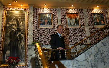 Lopera sube la escalera de su casa junto a un retrato del Cristo del Gran Poder y tres imágenes celebrando la Copa del Rey de 2005.