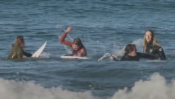 Un surfista con el neopreno rojo golpea la tabla de surf de otro surfista en Oceanside (California) este mes de octubre del 2021, mientras otros 3 surfistas se lo miran.