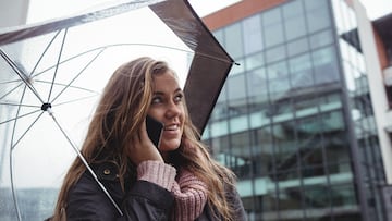 A woman holding an umbrella and talking on mobile phone at street