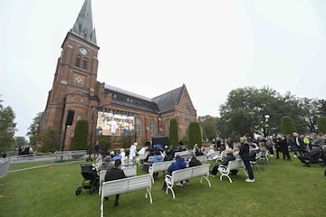 La gente sigue el funeral del difunto entrenador de fútbol sueco en una pantalla gigante, fuera de la iglesia de Fryksande en Torsby, Suecia. 