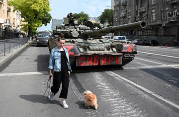Una mujer con un perro pasa junto a un tanque mientras los combatientes del grupo mercenario privado Wagner se despliegan en una calle cerca de la sede del Distrito Militar del Sur en la ciudad de Rostov.