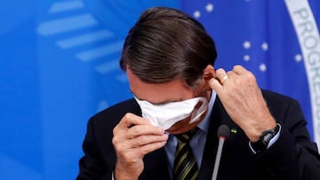FILE PHOTO: Brazil's President Jair Bolsonaro adjusts his protective face mask during a press statement to announce federal judiciary measures to curb the spread of the coronavirus disease (COVID-19) in Brasilia, Brazil March 18, 2020. REUTERS/Adrian