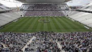 Vista general de exjugadores del club Corinthians en el centro de la cancha y aficionados en las graderías del estadio Arena Corinthians.