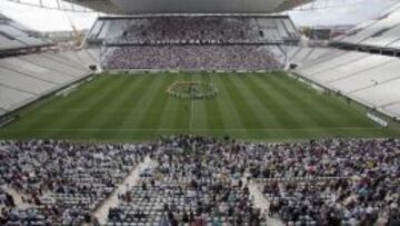 Vista general de exjugadores del club Corinthians en el centro de la cancha y aficionados en las grader&iacute;as del estadio Arena Corinthians.