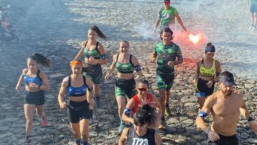 Participantes de la Fuerteventura Bestial Race 2023 corriendo por un suelo de piedras con un miembro de la organización persiguiéndoles con una bengala el sábado 6 de mayo del 2023 en Tuineje, Canarias.