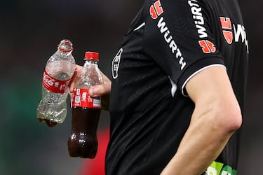 El árbitro Ricardo De Burgos recoge las botellas lanzadas al terreno de juego tras el segundo gol del Sevilla FC.