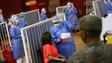 A healthcare worker talks to a woman as people receive doses of Russia's Sputnik V vaccine against the coronavirus disease (COVID-19) at the basket ball court at the River Plate stadium, in Buenos Aires, Argentina February 3, 2021. REUTERS/Matias Baglietto