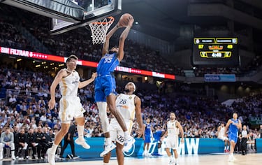 Los jugadores del Real Madrid, Hugo Gonz¨¢lez y Guerschon Yabousele, observan como el alero de Dallas Mavericks, Derrick Jones Jr., realiza un mate.