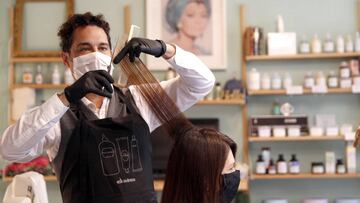 GRAF039. BILBAO, 03/05/2020.- El propietario y estilista Raúl de Andreas (d) realiza un corte en su peluquería protegido con guantes y mascarilla. La Asociación Nacional de Perfumería y Cosmética (Stanpa) ha elaborado una Guía de Recomendaciones de referencia básica de cara a la recuperación de la actividad de los salones de peluquerías en España. Las peluquerías pueden abrir a partir de este lunes, pero las ganas y la necesidad de volver al trabajo se combinan con las dudas sobre las personas que pueden atender y la falta de material sanitario EFE/LUIS TEJIDO.