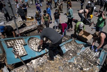 MINNEAPOLIS, MN - MAY 30: People work to clean up outside a burned building on May 30, 2020 in Minneapolis, Minnesota. Buildings and businesses around the Twin Cities have been looted and destroyed in the fallout after the death of George Floyd while in police custody. Police Officer Derek Chauvin has been charged with third-degree murder and manslaughter in Floyd's death. Stephen Maturen/Getty Images/AFP == FOR NEWSPAPERS, INTERNET, TELCOS & TELEVISION USE ONLY ==