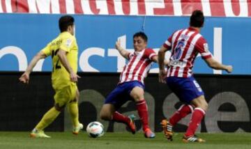 El centrocampista del Villarreal Joan Román (i) disputa un balón con el centrocampista uruguayo del Atlético de Madrid Cristian Rodríguez (c), ante su compañero, el centrocampista Koke Resurección (d).