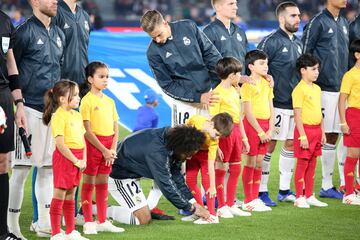 El lateral brasileño ata el cordón a un nhiño a la salida de los jugadores al terreno de juego.