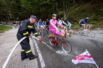 Un bombero moja la carretera durante el paso de los participantes en la Red Bull Goni Pony, una carrera cuya protagonista es la legendaria Rog Pony, una bicicleta plegable típica de Eslovenia. La prueba, con salida en Kranjska Gora, pasa por Vrsic, el puerto de montaña más alto de eslovenia con 1.611 m de altitud y multitud de serpentinas.