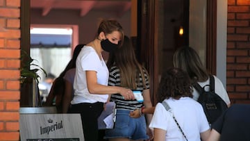 La trabajadora de un restaurante de Buenos Aires, toma la temperatura a sus clientes antes de su ingreso al establecimiento.