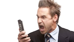 Closeup of stressed businessman holding a mobile phone and screams into it. Isolated on white background