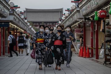 Women wearing face masks and traditional yukatas (a light cotton kimono) walk along Nakamise shopping street on August 26, 2021 in Tokyo, Japan. Japan suspended the use of 1.63 million doses of Moderna Covid-19 vaccines today after reports that some of th