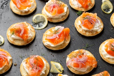 Unta queso crema sobre blinis, coloca salmón ahumado y decora con eneldo fresco.