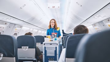 Interior of international airplane with passengers on seats and stewardess in uniform walking the aisle