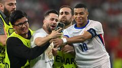 Stewards stop a pitch invader as he takes a selfie with France's forward #10 Kylian Mbappe during the UEFA Euro 2024 semi-final football match between Spain and France at the Munich Football Arena in Munich on July 9, 2024. (Photo by Fabrice COFFRINI / AFP)