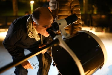 Un hombre mira a través de un telescopio en el techo del planetario distrital para ver un eclipse lunar en Bogotá, Colombia.