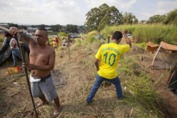 Integrantes del Movimiento de los Trabajadores Sin Techo (MTST) construyen viviendas improvisadas en una área que fue ocupada el pasado sábado situada a unos 4 kilómetros del estadio Arena Corinthians de Sao Paulo, una de las doce sedes del Mundial Brasil 2014 y que recibirá seis partidos del evento deportivo, entre ellos el inaugural del 12 de junio. De acuerdo con el movimiento, las familias que ocuparon el terreno, abandonado desde hace más de 20 años, vivían en áreas "de riesgo", "en favelas o sin condiciones para pagar el alquiler por culpa de la especulación inmobiliaria en la región, resultado de la construcción del estadio de apertura del Mundial".