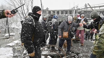 A Ukrainian soldier helps an elderly woman to cross a destroyed bridge during the evacuation by civilians of the city of Irpin, northwest of Kyiv, on March 8, 2022. (Photo by Sergei SUPINSKY / AFP)