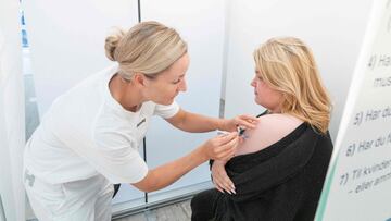 (FILES) In this file photo taken on September 11, 2021 a medical personnel administers a Covid-19 vaccine to a woman at a pop-up vaccination center in a Bilka supermarket in Ishoej, Denmark, on a vaccination day- - Denmark, which in February lifted all cu