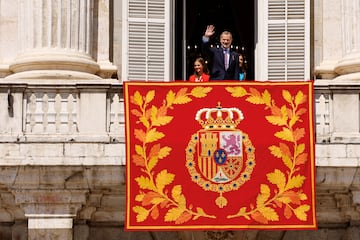 El rey Felipe VI saluda desde un balcón a la plaza de Oriente, junto a la reina Letizia y su hija, la princesa Leonor, después de asistir al relevo de la Guardia Real durante las conmemoraciones del décimo aniversario de la proclamación del rey Felipe VI en el Palacio Real de Madrid.