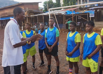 Mustapha Bangura, entrenador del equipo de ftbol del Centro de Servicios Correccionales para Mujeres, habla con las jugadoras durante el entrenamiento en el campo de ftbol comunitario Parade en Freetown.