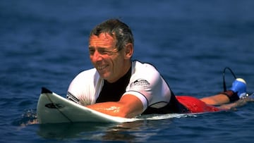 Alan Green, fundador de Quiksilver, posando sobre su tabla de surf.