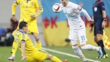 Milivoje Novakovic trata de llevarse el balón ante Artem Fedetskiy.