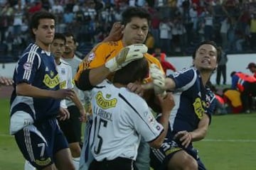 Un 10 de abril de 2005, Colo Colo jugaba de local ante la U por el Apertura de ese año. Los azules ganaban 1-0 con gol de Nelson Pinto (25'), pero los albos empataron con taco de Angel Carreño a los 82'. Ahí se formó la gresca entre los jugadores, cuando Jorge Valdivia le gritó el gol en la cara al portero de la U, Johnny Herrera.