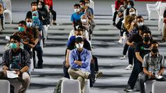 People wearing protective masks sit as they queue for their turn to receive a dose of the AstraZeneca coronavirus disease (COVID-19) vaccine at the Istora Senayan Stadium in Jakarta, Indonesia, June 16, 2021. REUTERS/Ajeng Dinar Ulfiana