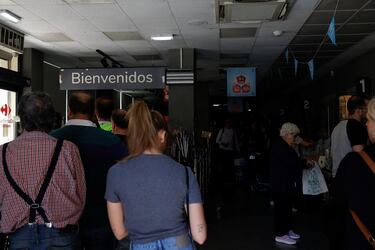 La gente compra en un supermercado con solo luces de emergencia encendidas durante un apagón, en Madrid, España.
