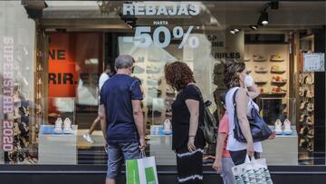 Varias personas observan el escaparate de una tienda con carteles de rebajas