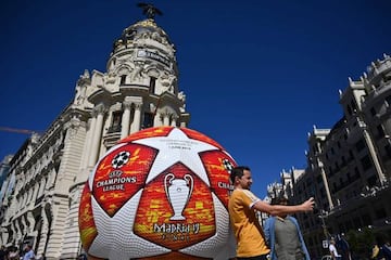 A passerby in Madrid takes a selfie with a giant replica of the Champions League ball.