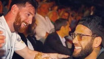 Lionel Messi y Dani Alv&eacute;s sonriendo mientras se dan un apret&oacute;n de manos.