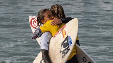 Luc&iacute;a Machado y Melania Su&aacute;rez se abrazan con sus tablas de surf reci&eacute;n salidas del agua tras la manga de la repesca que las enfrent&oacute; en el Vissla ISA World Junior Championship disputado en Huntington Beach (California, Estados