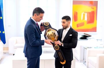 El presidente del Gobierno, Pedro Sánchez (i), recibe al luchador de artes marciales mixtas Ilia Topuria (d), que le muestra el cinturón de la UFC,  tras proclamarse campeón mundial.