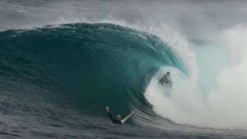 Un surfista surfea una ola de 2 metros en forma de tubo mientras otro alza los brazos en señal de celebración. En Australia.